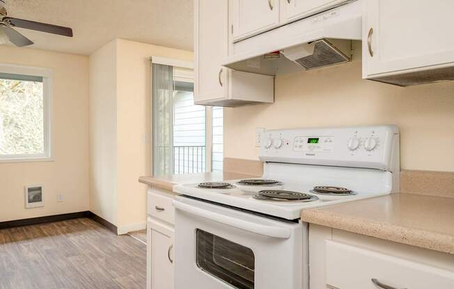 A white stove and oven in a kitchen with a fan on the ceiling.