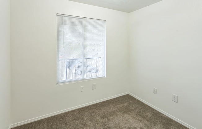 an empty room with a window and a carpet