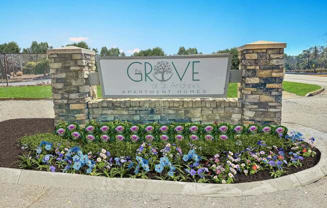 A sign for Grove at Andrews Apartment Homes is surrounded by flowers.