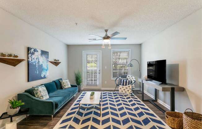 A living room with a blue couch and a rug.