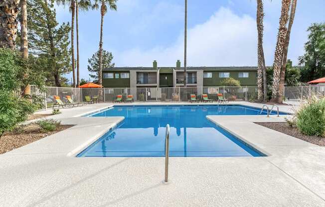 A swimming pool surrounded by palm trees and a building in the background.