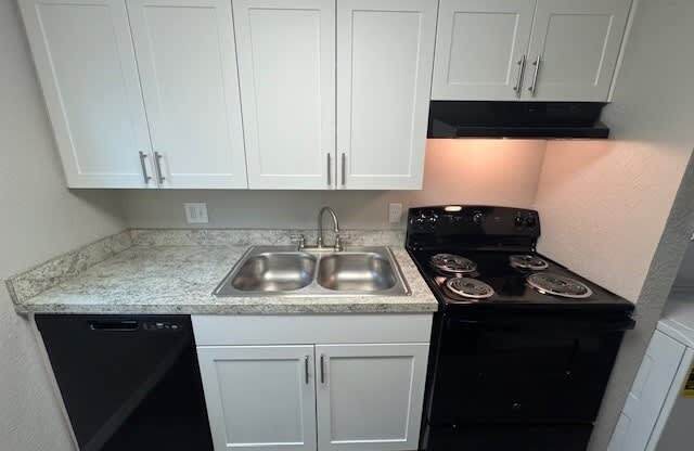 A kitchen with black appliances and white cabinets.