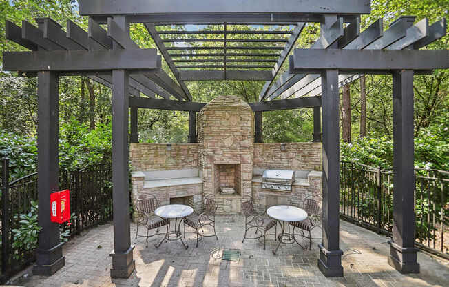 A patio with a fireplace and chairs under a pergola.