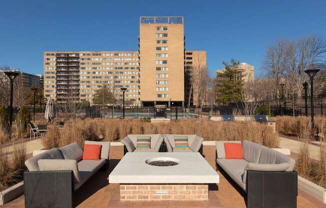 A patio with a table and chairs in front of a tall building.