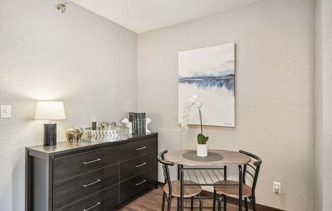 A dining table with chairs and a cabinet with drawers is in a room.