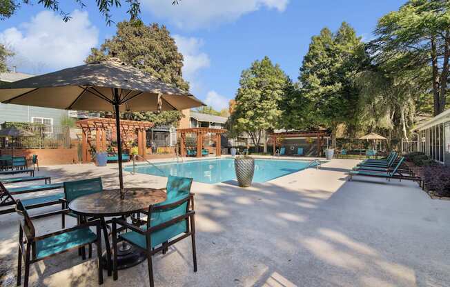 A patio with a table and chairs and a pool in the background.