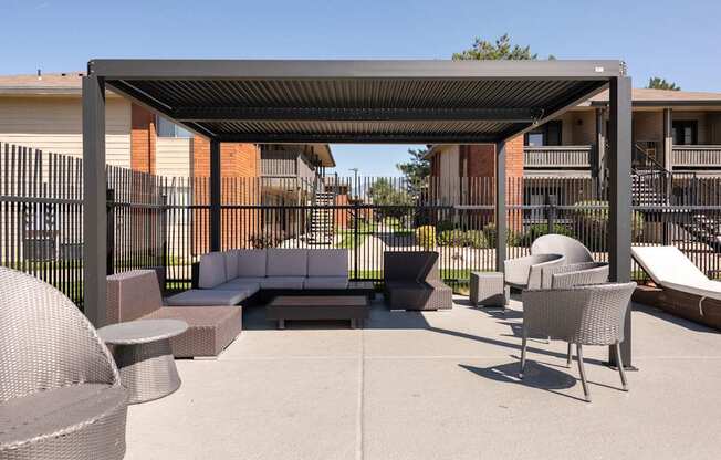 a lounge area with couches and chairs under a shade