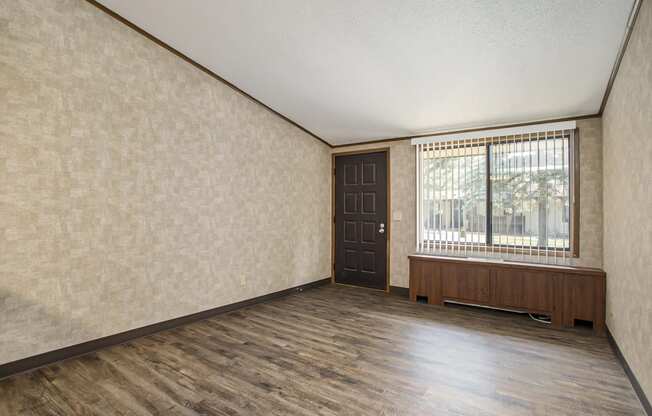 an empty living room with a large window and wooden floors