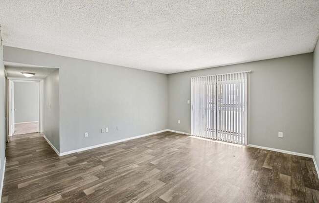 A room with wooden flooring and a window with blinds.
