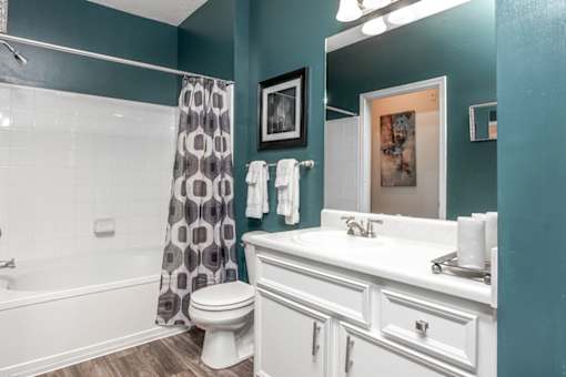 A white toilet sits in a bathroom with a blue wall.