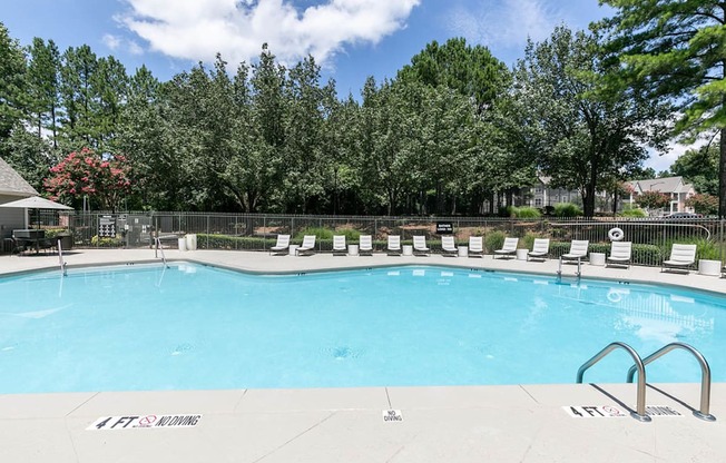 a swimming pool with chairs around it and trees in the background at Gwinnett Pointe, Norcross, GA