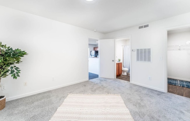 an empty living room with a rug and a bathroom in the background