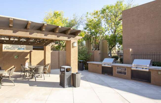 a patio with a barbecue grill and a table and chairs