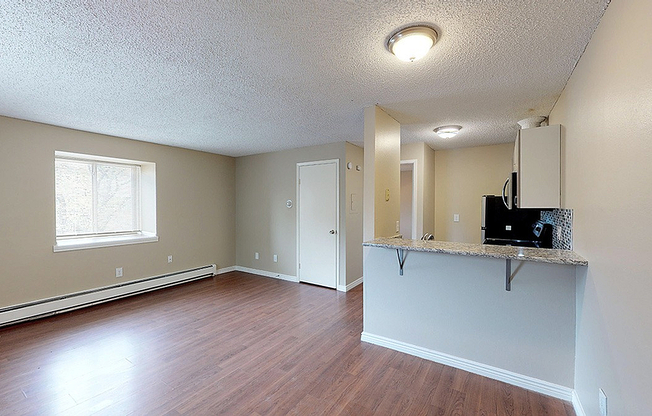Spacious and modern open-concept living area with wood flooring and a sleek kitchen peninsula.