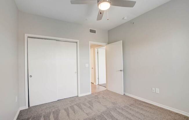 A room with a ceiling fan and carpeted floor.