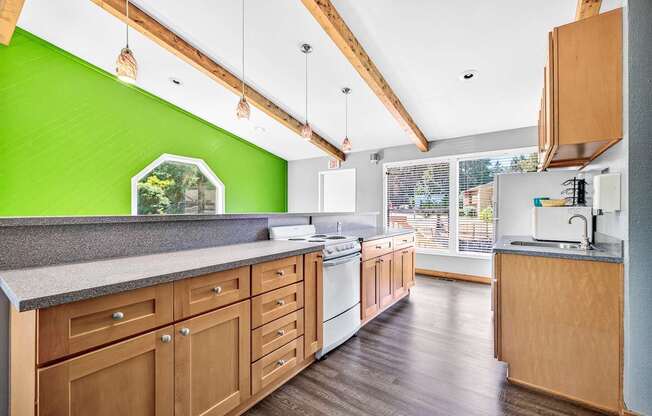 A kitchen with wooden cabinets and a green wall.