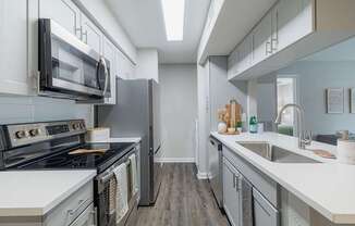 A modern kitchen with a stove, microwave, and refrigerator.