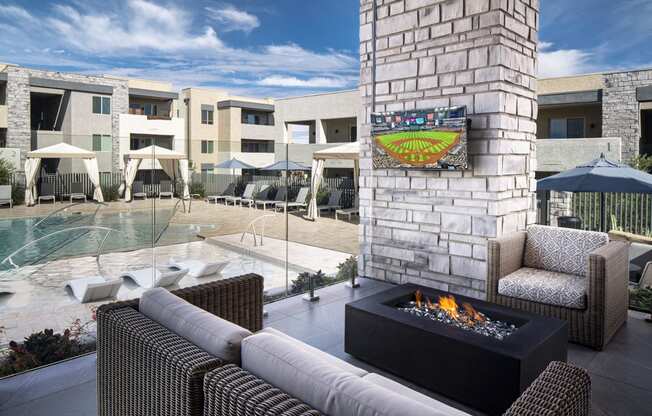 an outdoor patio with a fireplace and a pool in the background