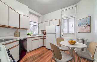 a kitchen with white cabinets and a white table and chairs