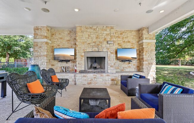 A patio with a stone fireplace and a TV mounted above it.