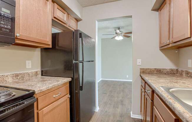 A kitchen with a black refrigerator and wooden cabinets. Omaha, NE Evergreen Terrace Apartments