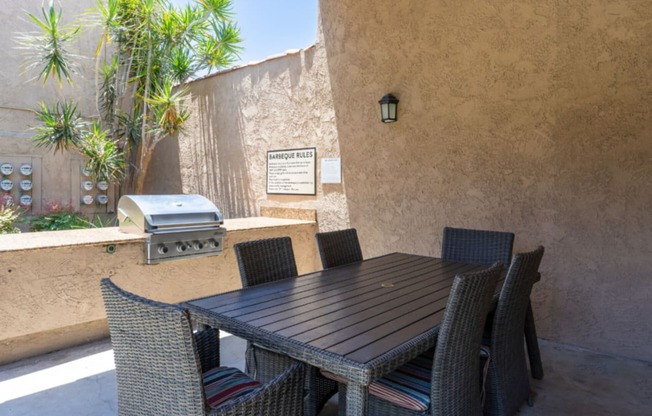 a patio with a table and chairs and a grill