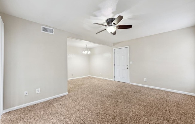 the spacious living room with ceiling fan and carpet