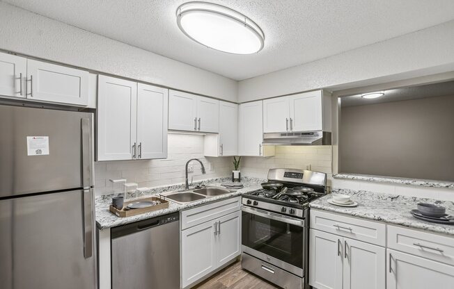 A kitchen with a refrigerator, stove, and sink.