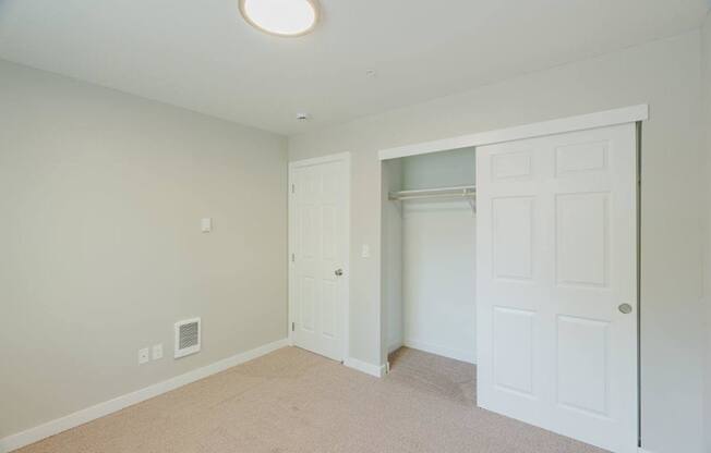 A room with a white door and a carpeted floor.