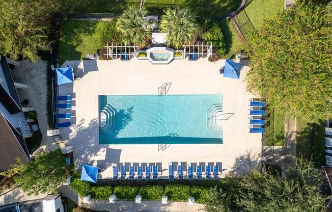 arial view of a swimming pool with chaise lounge chairs and trees in the background