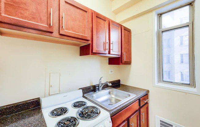 kitchen with window, wood cabinetry and electric range at baystate apartments in washington dc