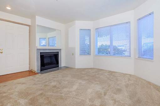 A living room with a fireplace and carpeted floor.
