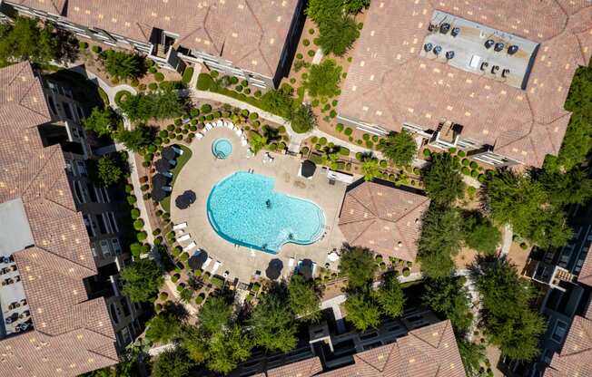 an aerial view of a swimming pool surrounded by trees and buildings