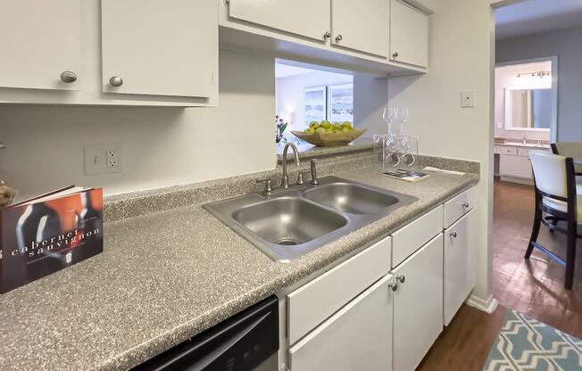 a kitchen with a sink and a counter top with white cabinets