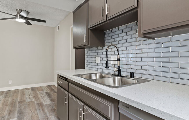 Tiled kitchen with stainless steel sink, microwave, and fridge.