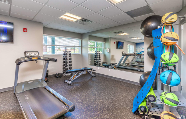 a gym with exercise equipment and weights in the corner of a room