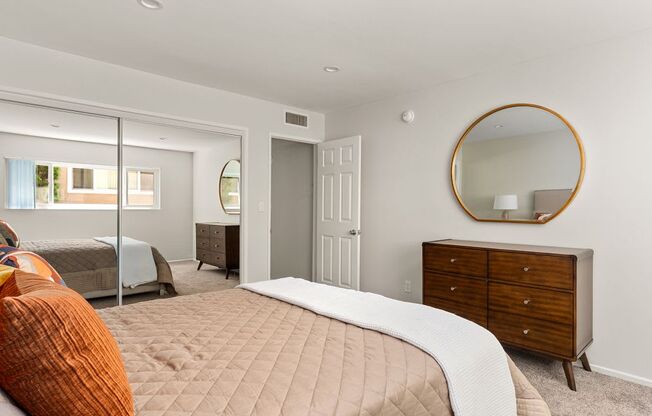 A bedroom with a bed, dresser, and mirror.