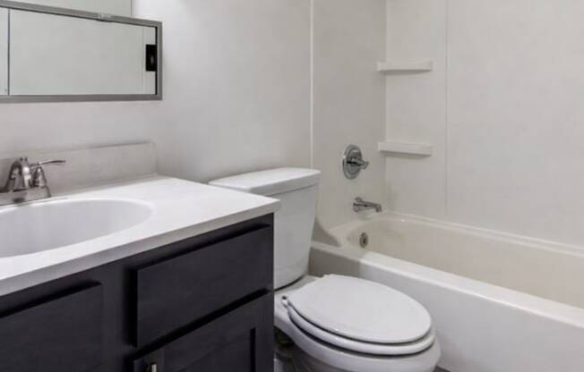 A white toilet sits next to a white sink in a bathroom.