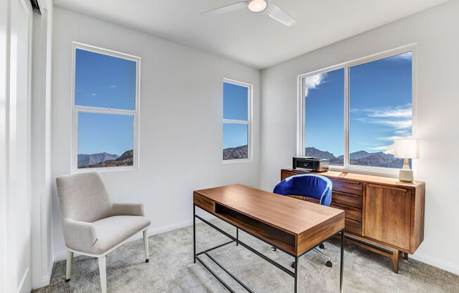 a bedroom with a desk and three windows