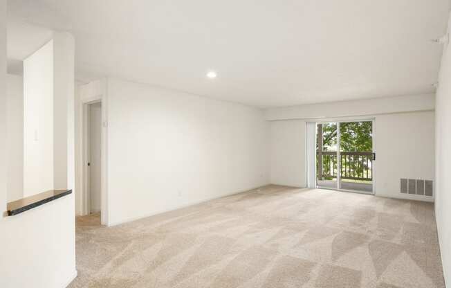 the living room and dining room of a house with white walls and a large window