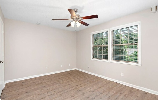 an empty living room with a ceiling fan and a window