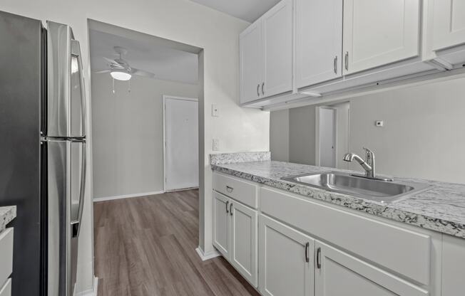 a kitchen with white cabinets and a sink and a refrigerator