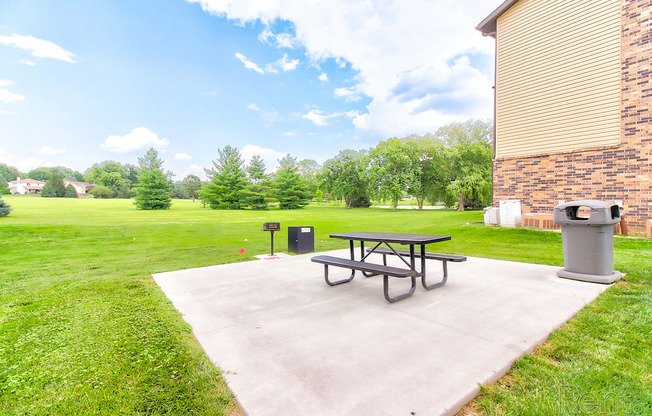 a patio with a picnic table next to a building and a field