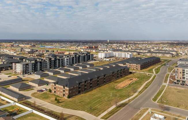 A large apartment complex is surrounded by smaller buildings and a road.