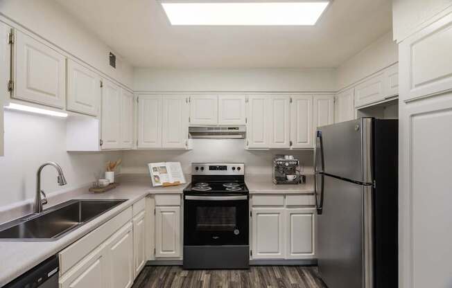 A kitchen with white cabinets and a black fridge.