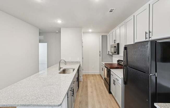 A kitchen with black appliances and white cabinets.