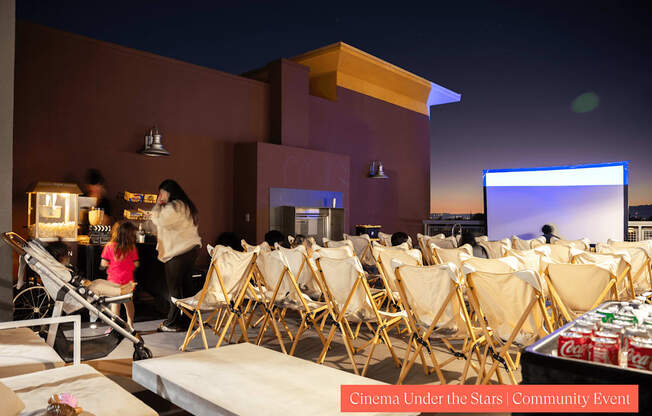 A group of people are sitting in chairs outside watching a movie.