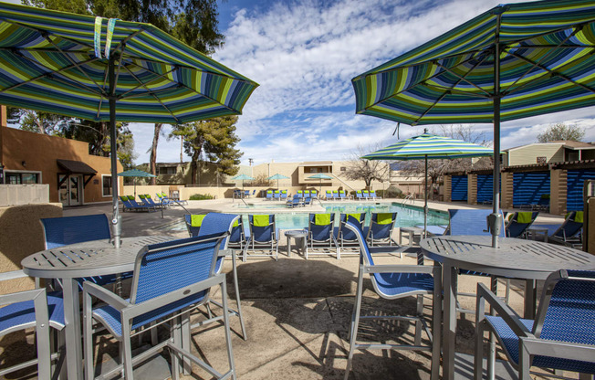 a group of tables and chairs with umbrellas next to a pool