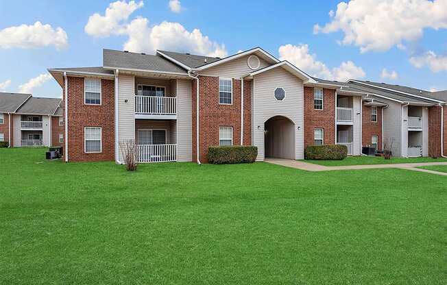 Apartment complex with red brick buildings and green lawns.