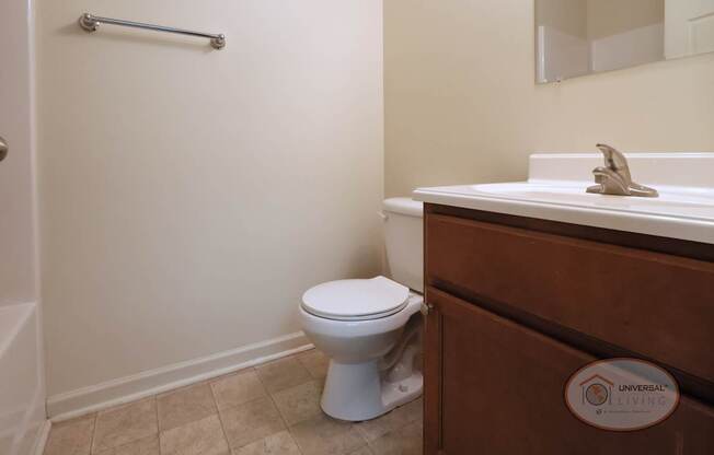 A white toilet and sink in a bathroom with vinyl flooring and white walls.